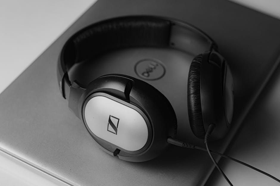 Black and white photo of headphones resting on a laptop.