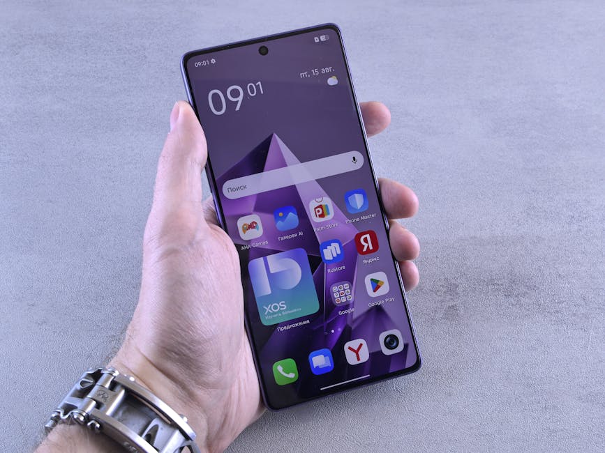 Close-up of a hand holding a smartphone displaying various apps on screen.