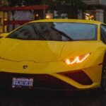 Vibrant yellow Lamborghini in urban setting during rain, capturing luxury and speed.