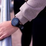 A close-up shot of a hand wearing a digital smartwatch, showcasing modern wearable technology outdoors.
