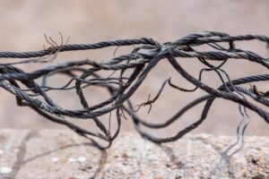 Detailed view of frayed and intertwined steel cables on a blurred background.