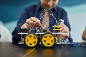 Child involved in building a small robot as part of a hands-on STEM education project, focusing on electronics.