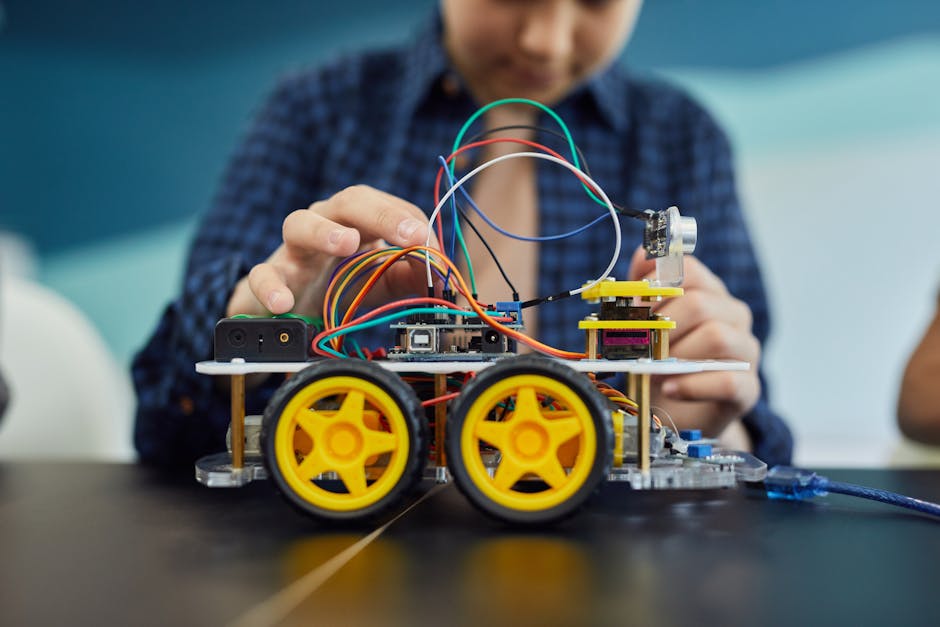 Child involved in building a small robot as part of a hands-on STEM education project, focusing on electronics.