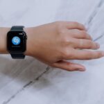 Close-up of a smartwatch on a wrist showing a music identification app with a marble background.