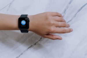 Close-up of a smartwatch on a wrist showing a music identification app with a marble background.