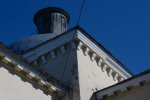 Low angle shot of building roof and dome under a bright blue sky, showcasing architectural detail.
