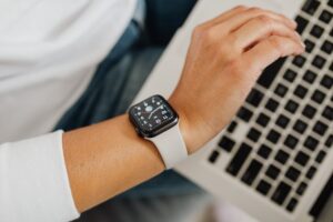 A person wearing a smartwatch working on a laptop, showcasing modern technology integration.